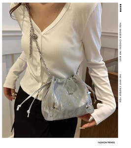 Detail of silver metallic bucket bag featuring bow decoration and chain strap textures