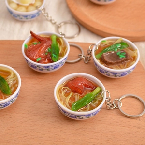 Miniature realistic food keychain with blue and white porcelain bowl on wooden background