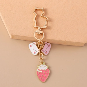 Detailed view of golden cat keychain with pink enamel cat and strawberry charms