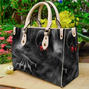 Gothic PU leather tote bag featuring dark skull pattern with red eyes in a garden setting