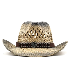 Chapeau de cowboy en paille avec bandeau en cuir et clous sur fond blanc pur