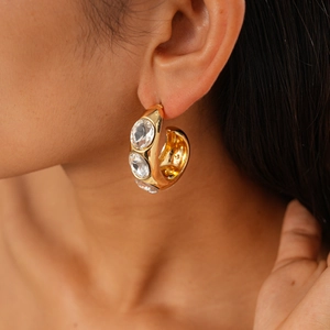 Close-up of golden multi-layer hoop earrings with three large sparkling crystals on model