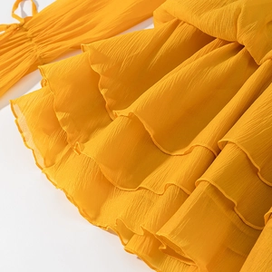 Detail showing ruffled edges and textured yellow fabric with delicate sleeve ties