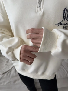 Close-up of the metal half-zipper collar and Sports WISK embroidery on a beige sweatshirt