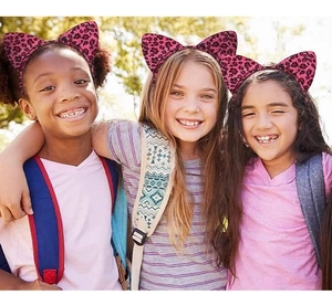 Three happy girls wearing pink leopard print cat ear headbands outdoors in sunny weather