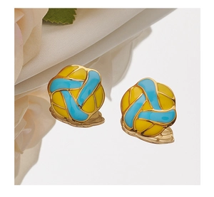 Macro shot of blue and yellow volleyball stud earrings with a gold finish on a mirror base
