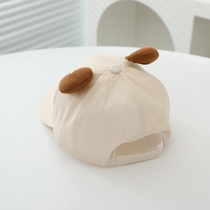 Detail view of beige kid's cap with plush ears and adjustable velcro strap back