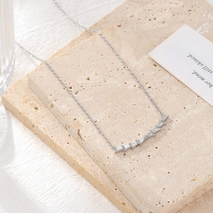 Minimalist silver smiley bar necklace with trapezoid-cut zircons on a textured stone