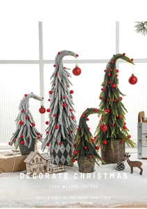Close-up of mini snowy Christmas tree with red berries in a geometric pot on a table