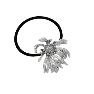Black elastic hair tie with irregular silver metal flower ornament on white background