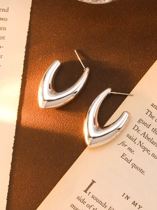 Close-up of silver V-shaped metallic earrings on vintage paper background