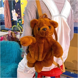 Detail view of a brown plush bear backpack with adjustable yellow straps on a model