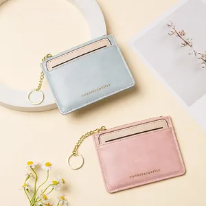Detail of light blue and pink faux leather card wallets with gold zipper and key ring