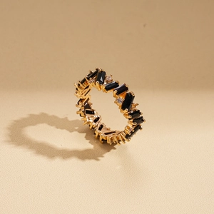 Detailed close-up of golden eternity ring featuring rectangular black gems and round diamonds