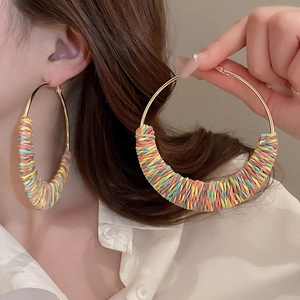 Macro detail of colorful woven candy-colored threads on golden hoop earrings