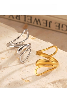 Detail view of gold and silver minimalist wavy rings on a stone textured surface