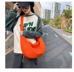 Street style shot of a bright orange large capacity oxford crossbody sling bag