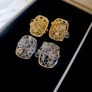 Macro detail of 18k gold and silver plated rectangular crystal earrings in a black box