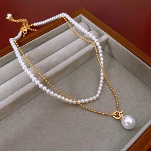 Gros plan d'un collier double épaisseur plaqué or avec perles dans un écrin de luxe