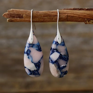 Detail of bohemian teardrop earrings featuring pink and blue stone textures on a branch