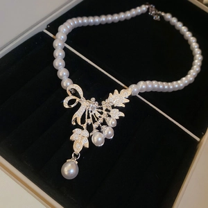 Detail of a vintage pearl necklace with diamond bow pendant in a black gift box