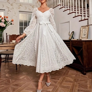 Détail de robe en dentelle blanche avec col en V, boutons et nœud dans un intérieur chic