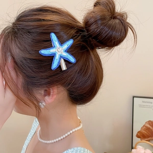 Gros plan d'une pince à cheveux étoile de mer bleue tissée avec strass sur un modèle
