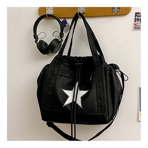 Detail of black nylon crossbody bag featuring a star logo and drawstring closure
