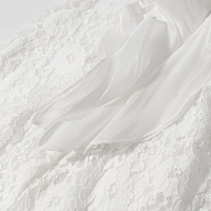 Détail de la dentelle blanche et de la texture plissée sur une robe longue à col en V profond