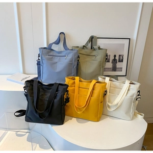 Collection of minimalist canvas tote bags in five vibrant colors displayed on a white stand