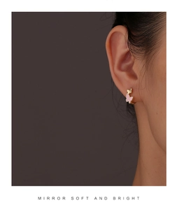 Close-up of elegant gold butterfly earrings with pink enamel on female model side profile