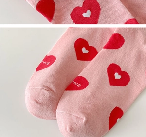 Detailed view of pink knitted socks featuring red hearts and love lettering design