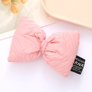 Detail of pink quilted leather bow accessory with diamond texture and small woven label