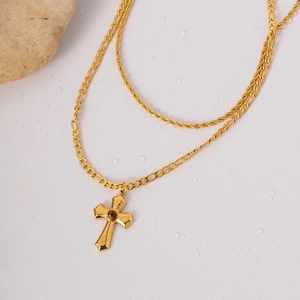 Detail of gold double-layered necklace featuring a cross pendant and brown tiger eye stone