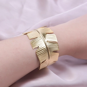 Detail of adjustable 18k gold-plated palm leaf cuff bracelet on woman's wrist