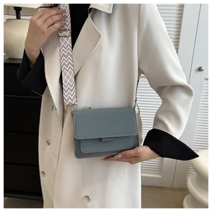 Close-up of stylish blue color-block crossbody bag with a wide geometric strap detail