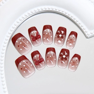 Handmade press-on nails with deep red cat-eye base, white dots and 3D floral bow accents