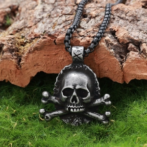 Detailed close-up of a vintage silver skull and crossbones pendant on a rustic wood background