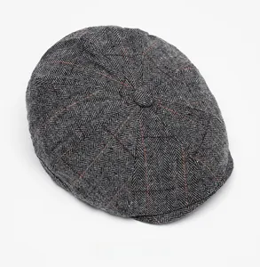 Top view of wool newsboy cap featuring grey herringbone pattern with orange windowpane checks
