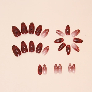Faux ongles amande rouges avec motifs roses et dégradé pailleté doré sur les pointes