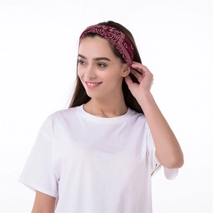 Women's burgundy paisley print sports headband worn by a model on white background