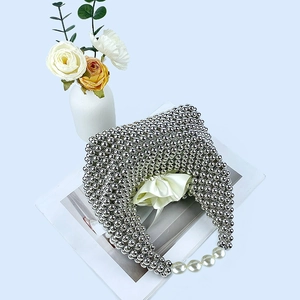 Top view of silver beaded pillow bag featuring pearl handle accents and magazine prop