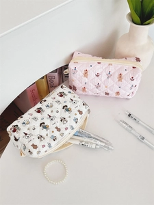 Close-up of quilted cotton pouches featuring cute cartoon bear and dog patterns with zippers