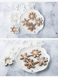 Detailed set of three white snowflake cookie cutters and finished iced gingerbread biscuits
