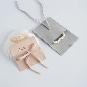 Detail shot of micro-fiber suede jewelry pouches in pink and grey with a pearl bracelet