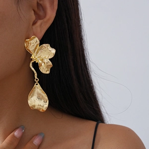 Close-up of elegant gold metal flower earrings on model showcasing petal texture and shine