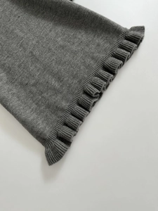Detail of dark grey knit fabric with ruffled lettuce edges and fine ribbed texture