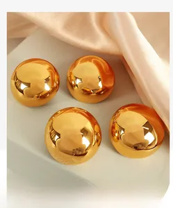 Detailed close-up of four polished gold domed earrings on a display with pink silk fabric