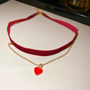 Close-up of double-layer red velvet choker with gold chain and heart pendant detail