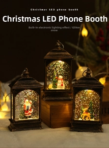 Detail of vintage telephone booth lantern with glowing LED Santa scene and sparkling snow